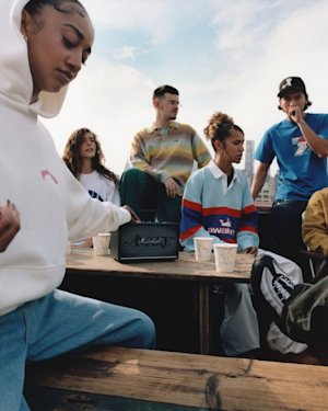 People gather around Marshall Acton III Awake NY Edition bluetooth speaker while skyscrapers loom in the background.