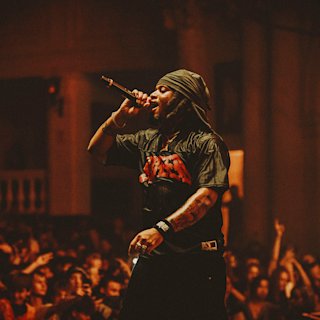 Denzel Curry performing in a gig wearing a headband.