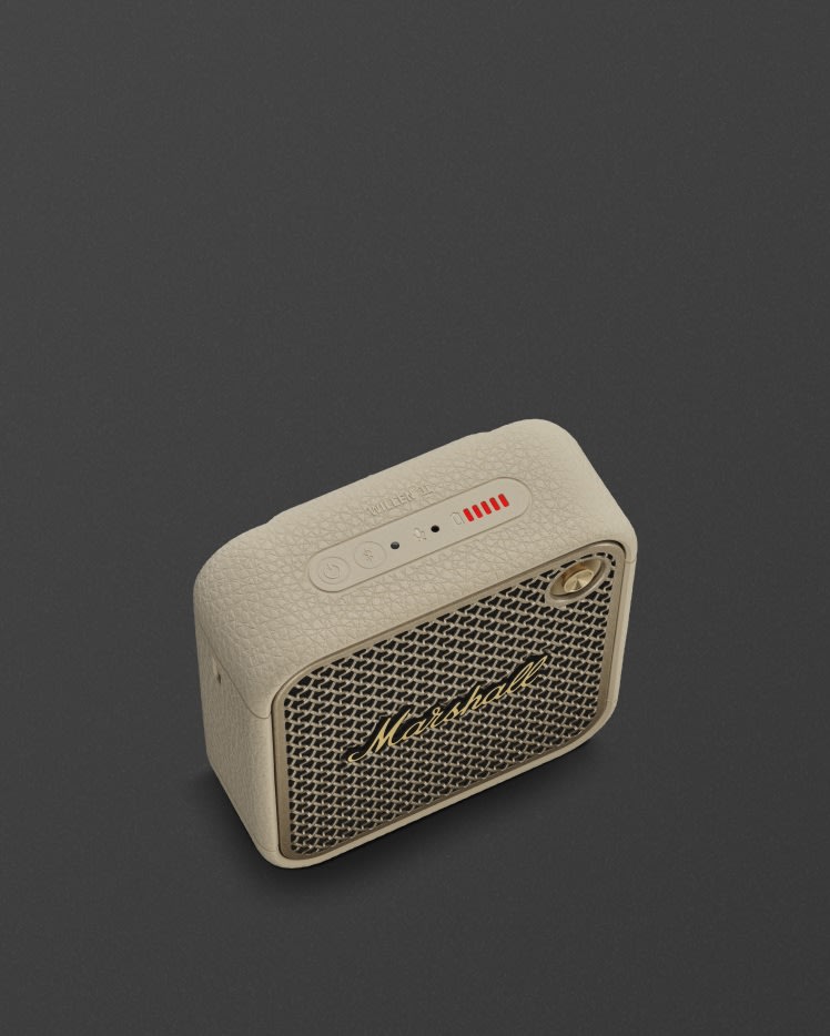 Marshall Willen II Cream bluetooth speaker with a control buttons on top, and a gold volume knob against a dark background.