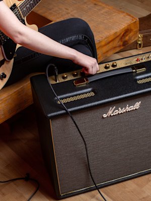 Guitarrista sentado afinando el Marshall Origin50 Combo