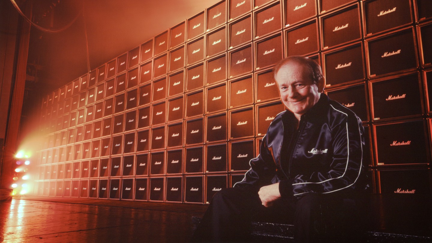Jim Marshall sat in front of a wall of Marshall Cabs.