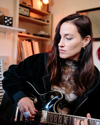 Theresa Wayman sitting and playing a guitar.