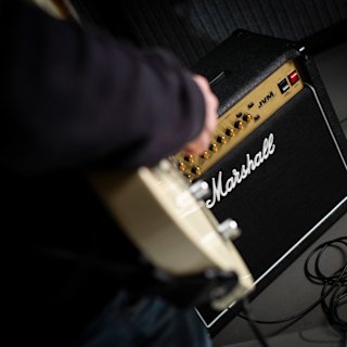 A guitarist åplaying his guitar which is connected to the Marshall JVM215 Combo amp.