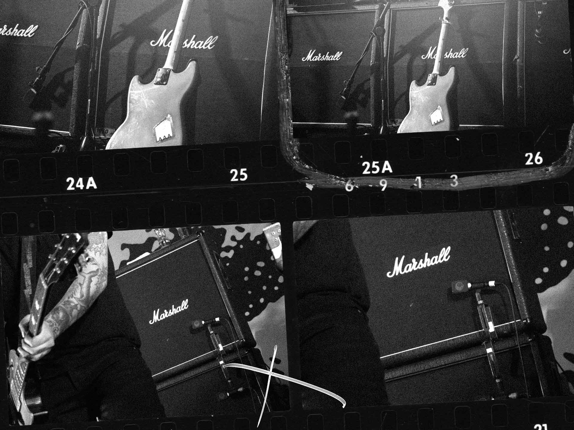 Collage en blanco y negro de una guitarra delante de amplificadores Marshall