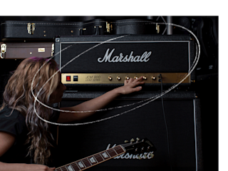 A woman is playing a guitar in front of a Marshall JCM800 2203 amp.