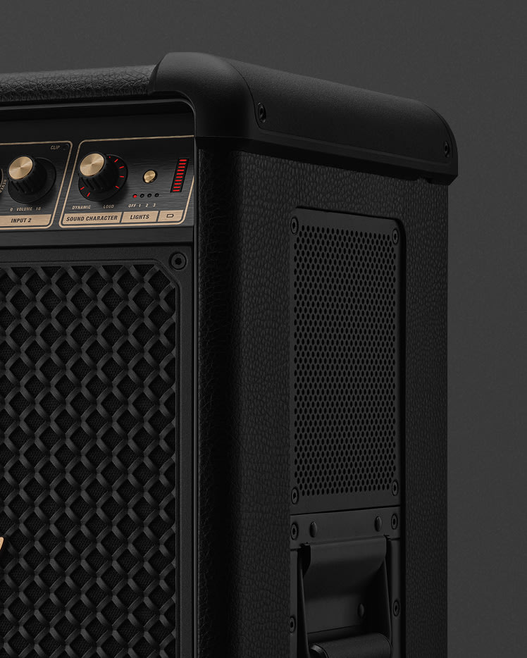 Close-up of the Marshall Bromley 750 with control knobs, textured grille, side handle, and mesh panel—evoking a party speaker’s power.