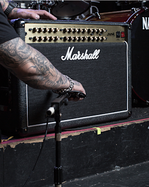 A person fixing the mic in front of the Marshall JVM410 Combo