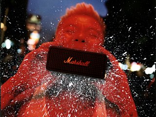 An edited red photo of Bohan Phoenix holding a Marshall Emberton II Black in front of his face.