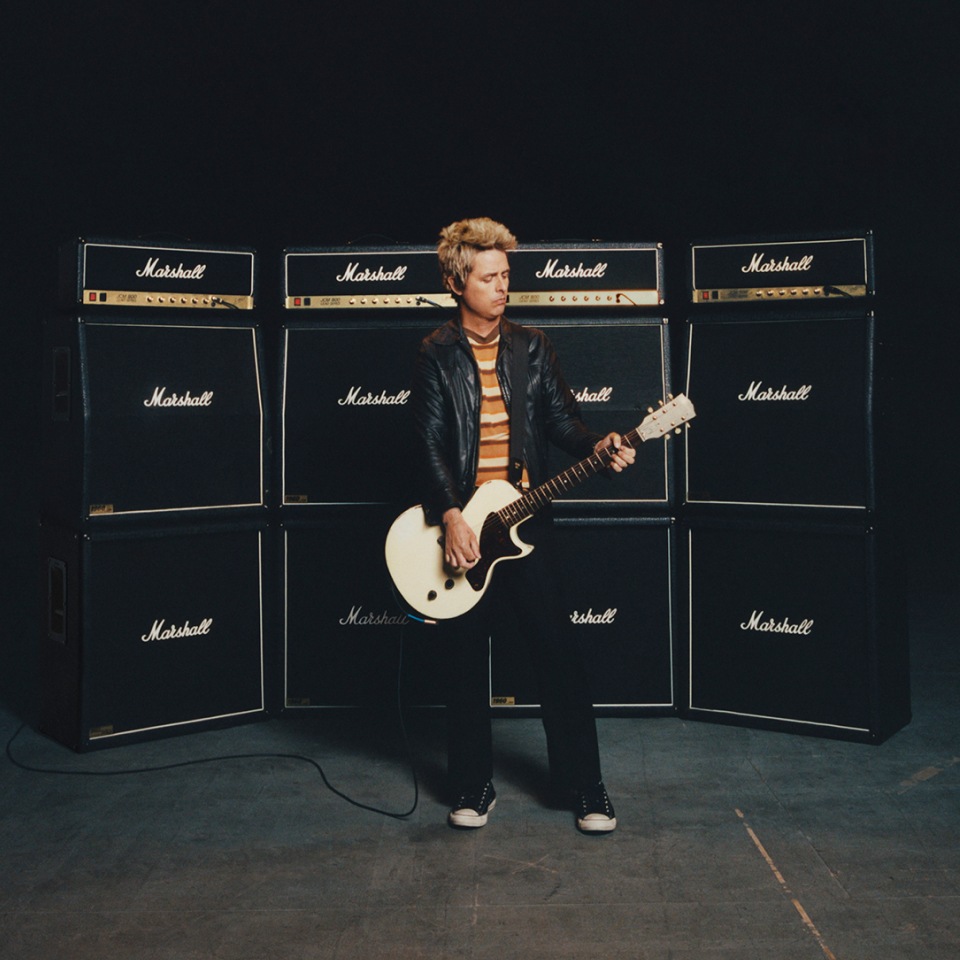 Billie Joe Armstrong posiert für ein Foto, während er in einem Studio eine an Marshall-Verstärker angeschlossene Gitarre spielt. 