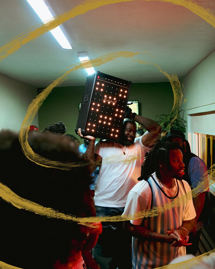 A man in a crowded room, raising the Marshall Bromley 750 party speaker.