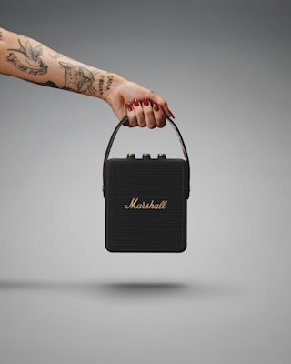 Someone is holding a Marshall Stockwell II speaker.