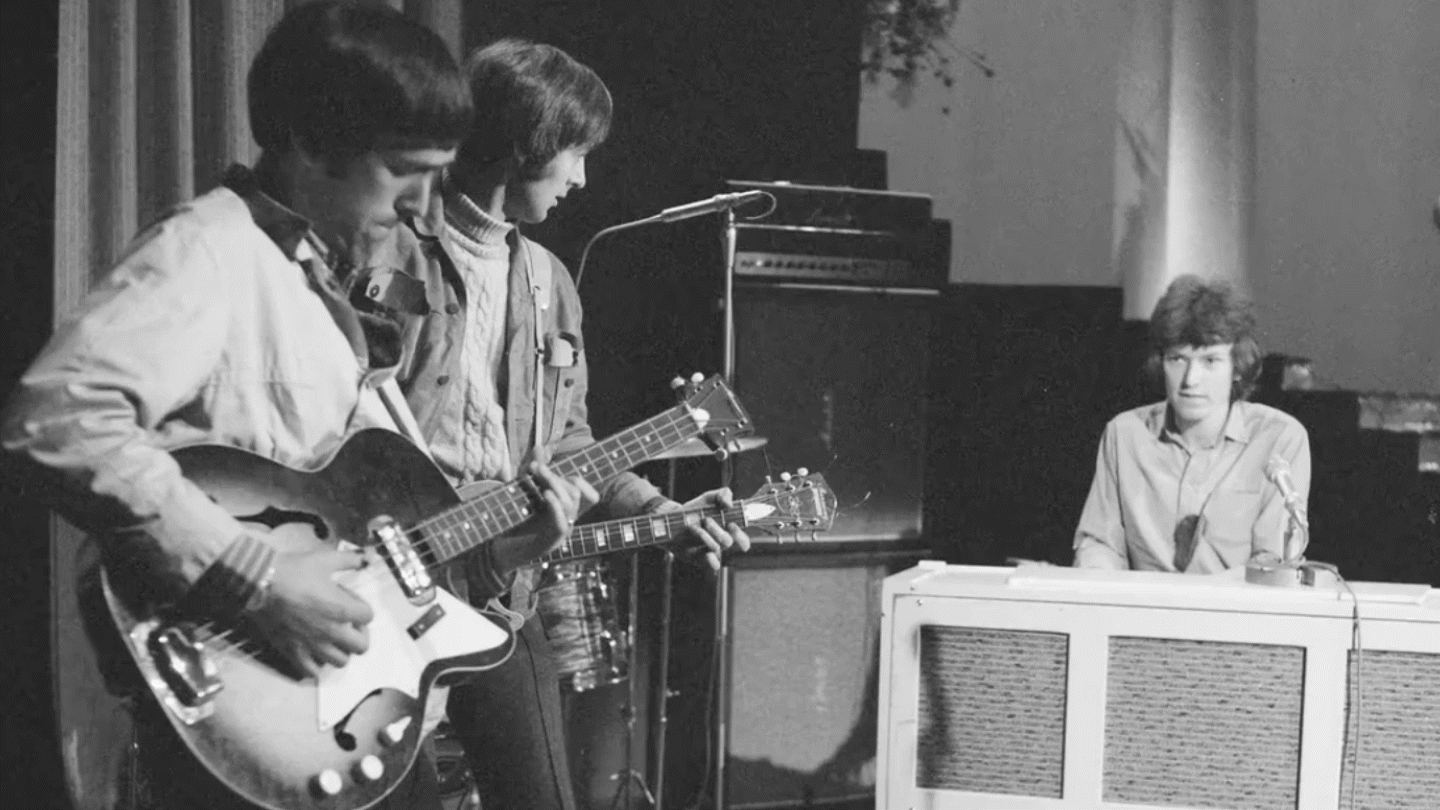 Gif en blanco y negro de un grupo tocando la guitarra con amplificadores Marshall de fondo.