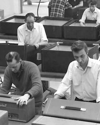 Black and white picture of people working side by side building Marshall amps.
