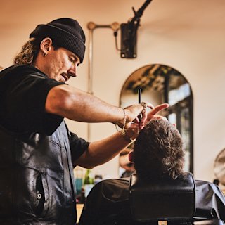 Un barbero recorta la barba de su cliente