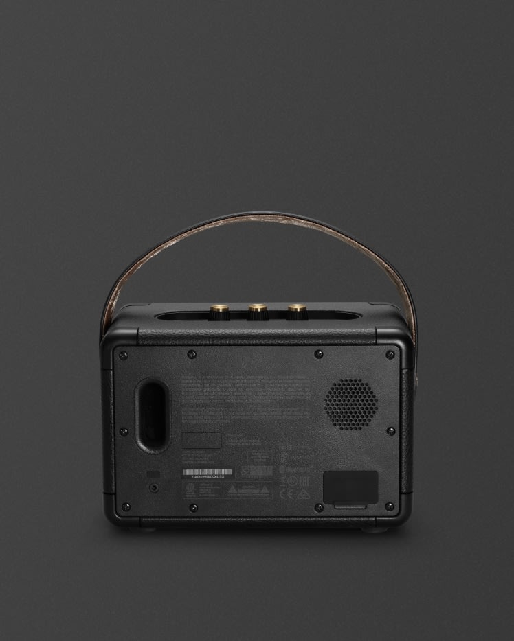 The portable speaker, Kilburn II Black and Brass, by Marshall, is a sleek black radio with a leather strap.