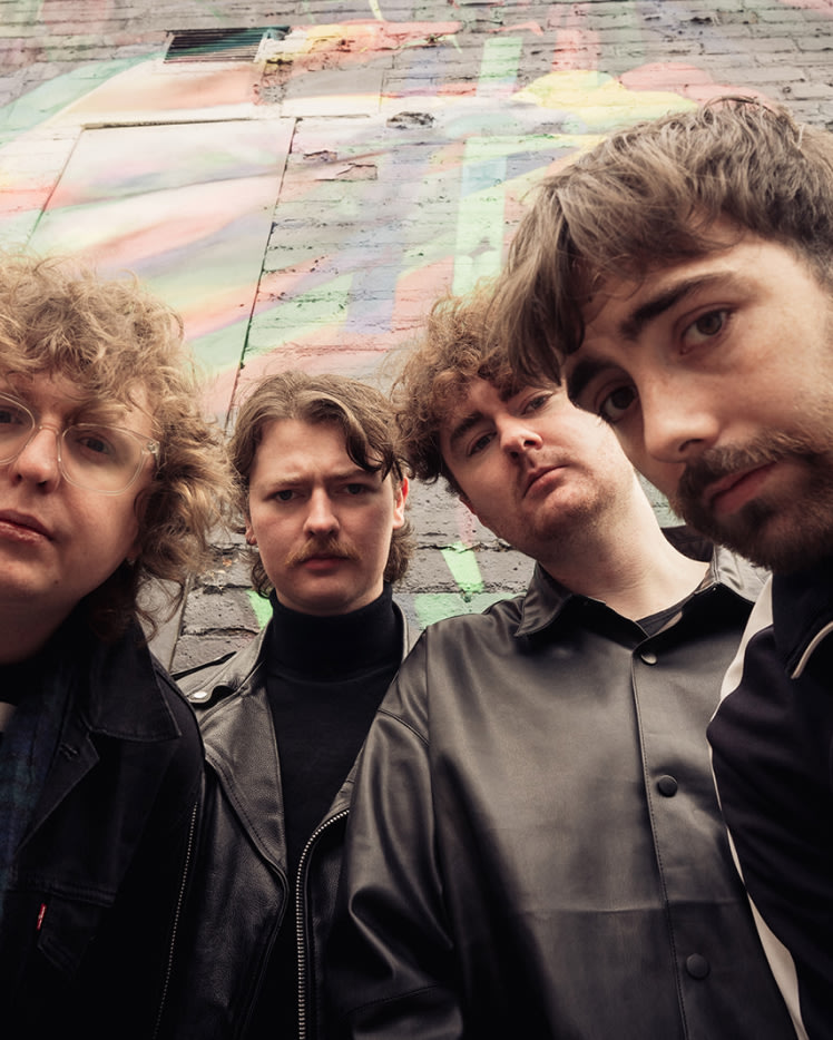 A group of men posing for a picture at a We Don't Like The People We've Become, Gallus CD launch event with Marshall speakers playing music in the background.