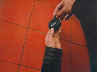 Marshall Motif II A.N.C. Black earbuds against a background of red tiles.