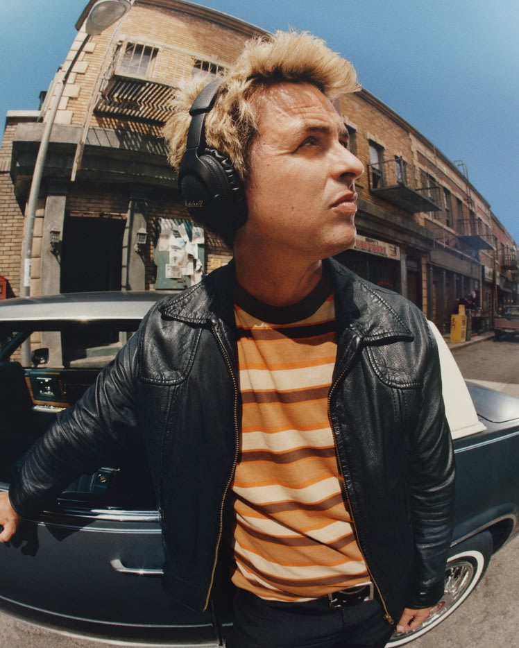 Billie Joe Armstrong con auriculares Marshall Monitor III A.N.C. Black, junto a un coche en una calle.
