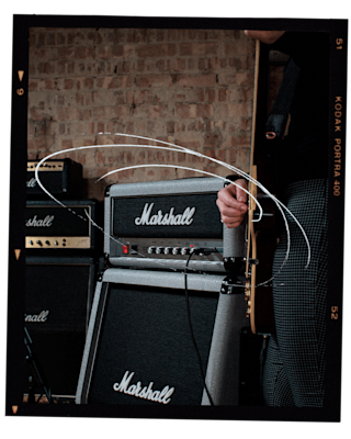 A man is playing a guitar in front of a Marshall Studio Jubilee Head amplifier.