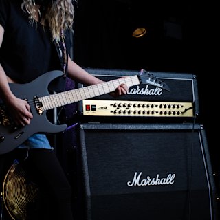 A person playing a guitar next to a Marshall JVM410 Head
