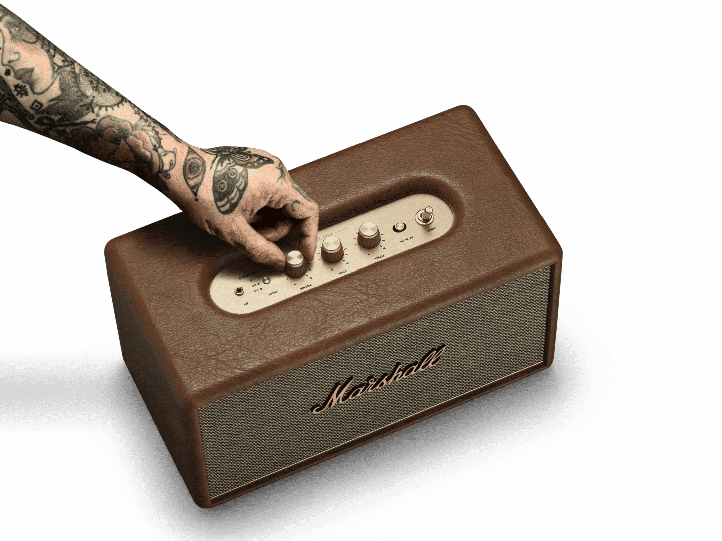 A man with tattoos is holding a Marshall Stanmore III speaker. 