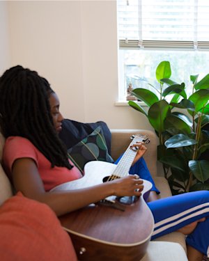 Little Simz sitting and playing acoustic guitar while Osiris playing keyboard.