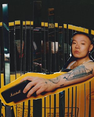 Bohan Phoenix holding a Marshall Emberton II Portable Speaker from inside a yellow taxi car.