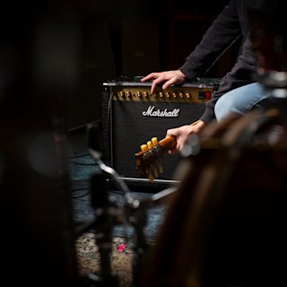 Un hombre toca una guitarra delante de un amplificador Marshall DSL20 Combo.