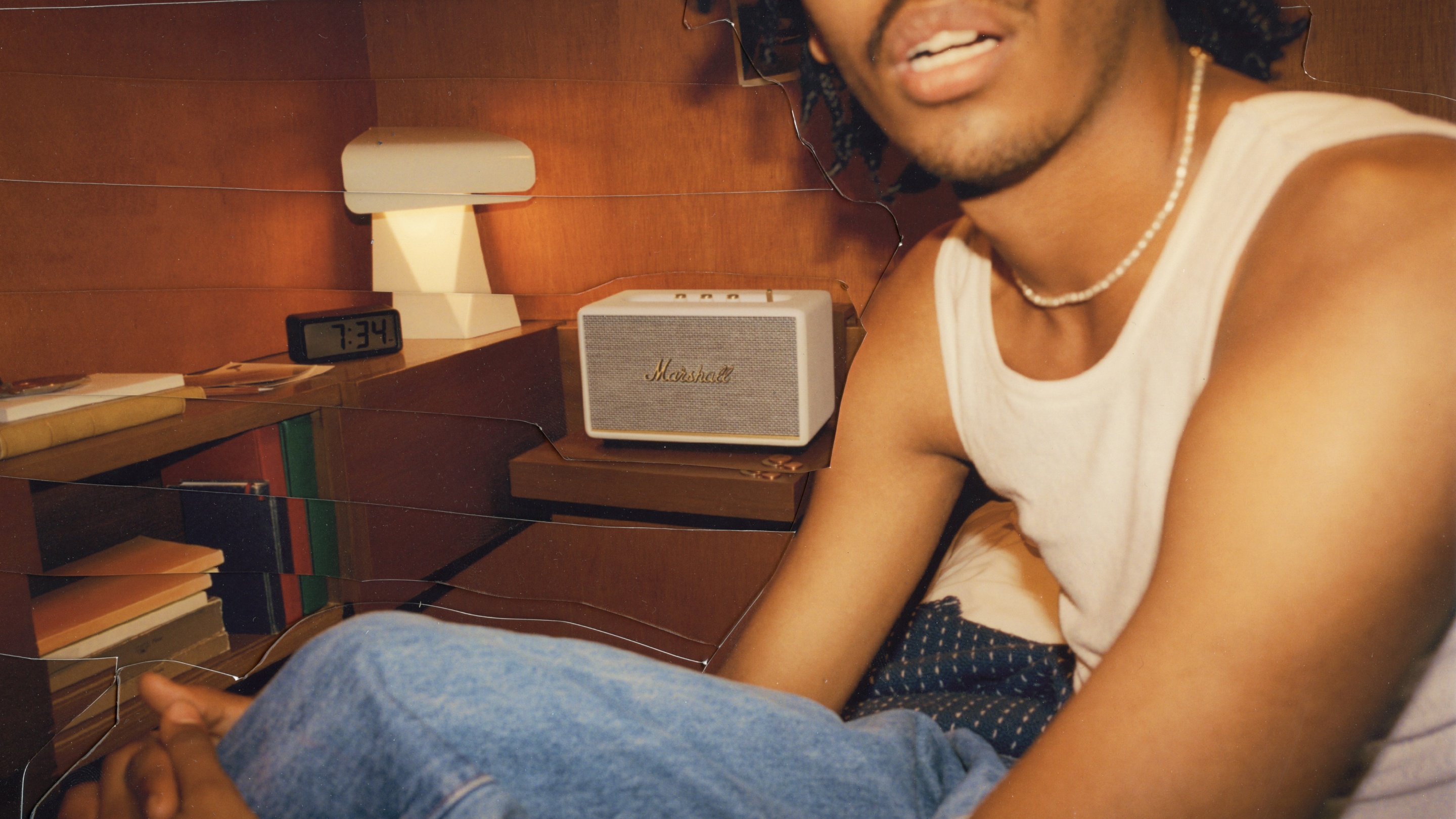 A man sitting on a bed next to a Marshall STANMORE III speaker.