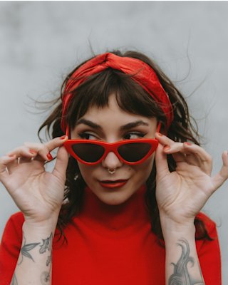 Gigi Gold looking over her red sunglasses