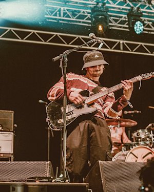 A guitarist playing his guitar in front of some Marshall amplifiers.