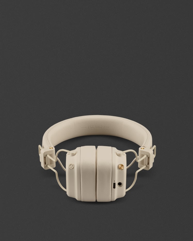 Ein Paar Marshall Major V Cream Over-Ear-Kopfhörer mit gepolsterten Ohrpolstern und verstellbarem Kopfband, abgebildet auf einem dunklen Hintergrund.