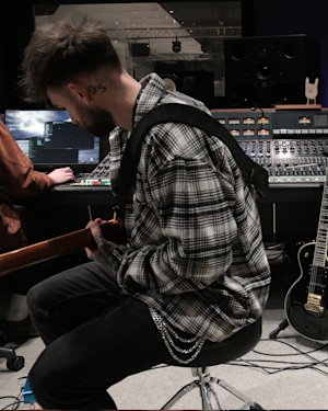 Un músico sentado junto a una guitarra en el estudio de grabación Marshall