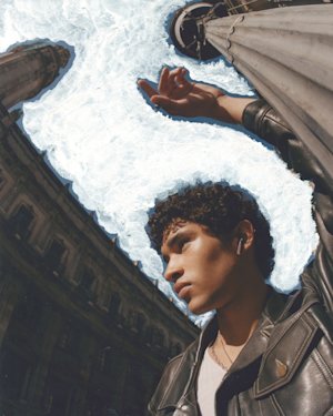 Man in a square listening to music from his Marshall Minor III Burgundy earbuds