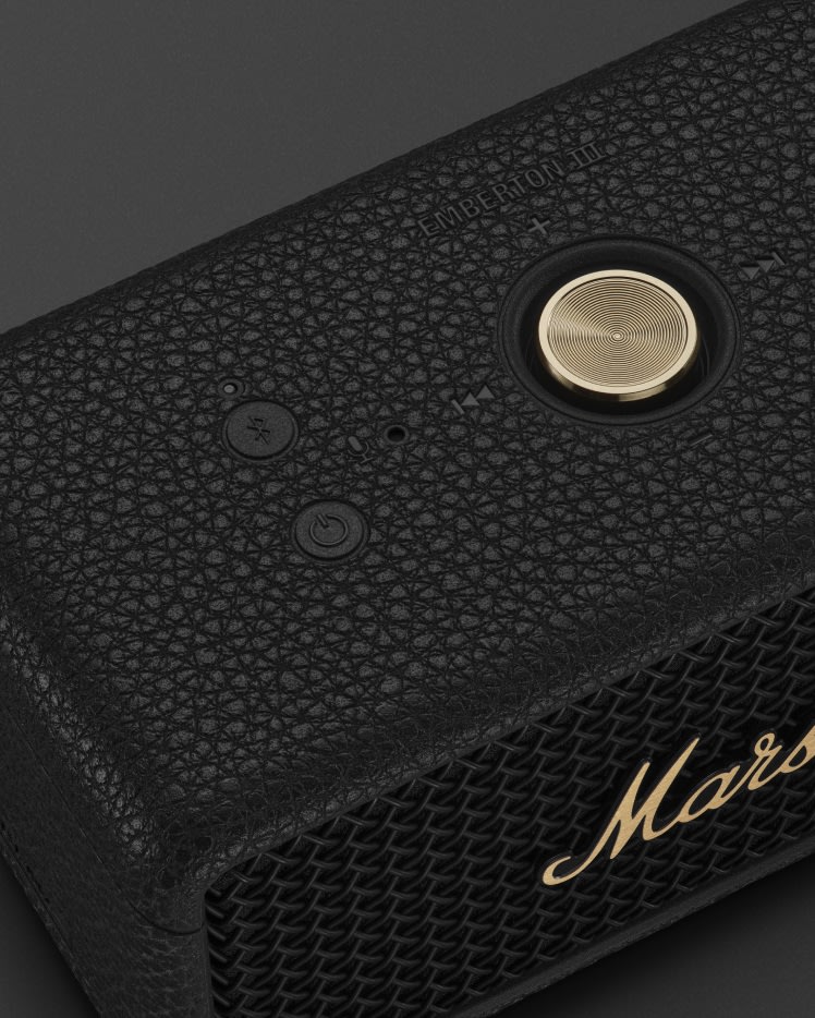 Close-up view of a Marshall Emberton III Black and Brass portable speaker showcasing the Bluetooth button, power button, and a gold rotary knob.