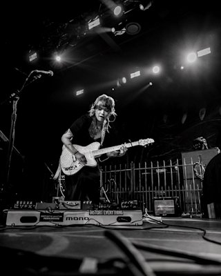 Black and white image of Yvette on stage playing in front of her pedal board