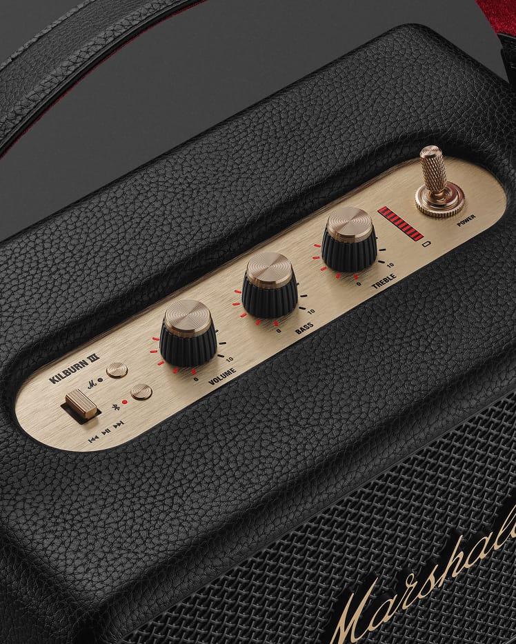 Close-up of the Marshall Kilburn III Black and Brass portable speaker control panel, displaying volume, bass, treble knobs, a power switch, and an input switch labeled Bluetooth and Aux.