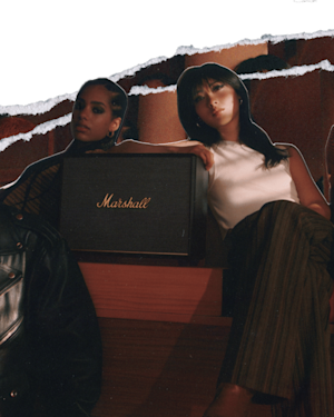 Eine Gruppe von Menschen sitzt auf einer Bank mit einem Marshall WOBURN III Mikrofon und Lautsprecher.