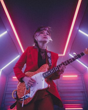 Yvette playing guitar in a room lit with LED lights