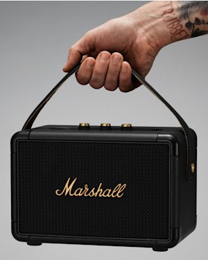 Mano cubierta de tatuajes sosteniendo un Kilburn II negro y latón.