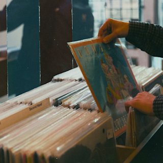 Someone holding and reading the cover of a vinyl in a record store