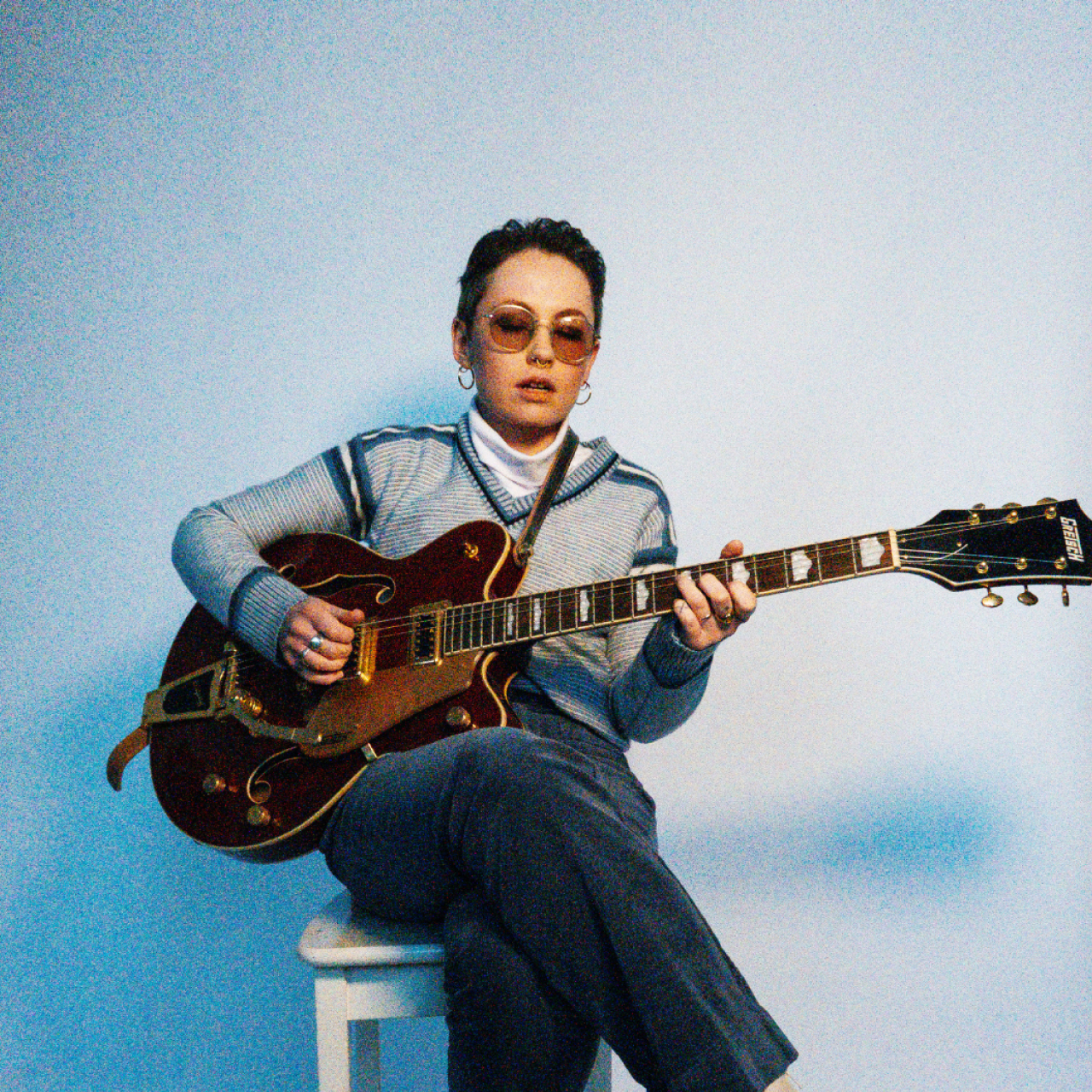 La artista Nia Wyn toca la guitarra en una silla