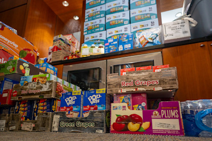  Boxes of snacks, fruit, and drinks are stacked in a USO center, ready for distribution to visitors.