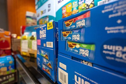 Boxes of Nutri-Grain bars stacked on a  shelf with other snack items in the background.