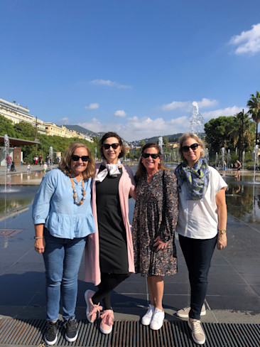 Four women standing together outdoors on a sunny day.