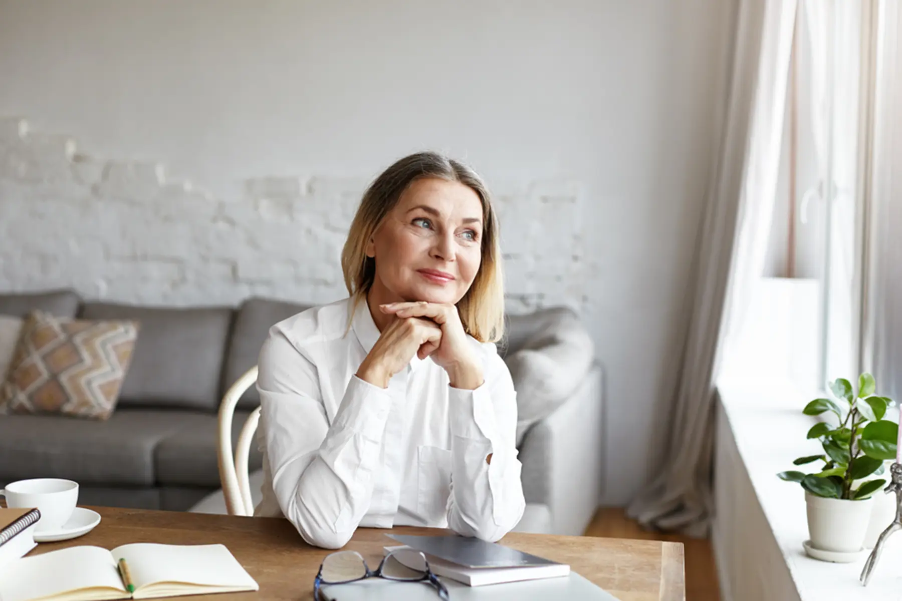 Middle aged woman sitting at a desk looking out the window.