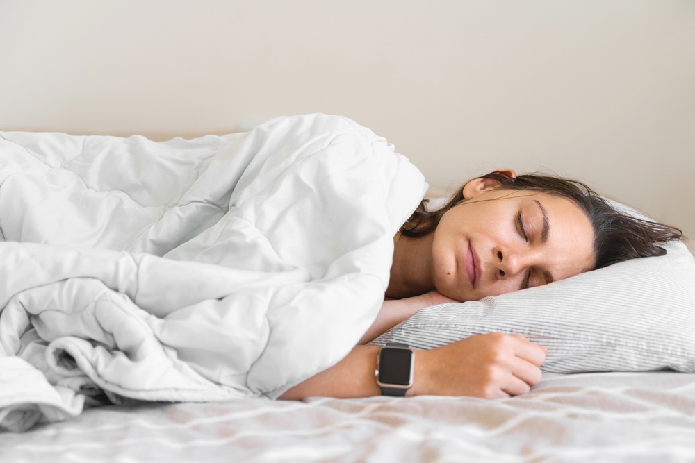 A woman sleeps on her side in bed.