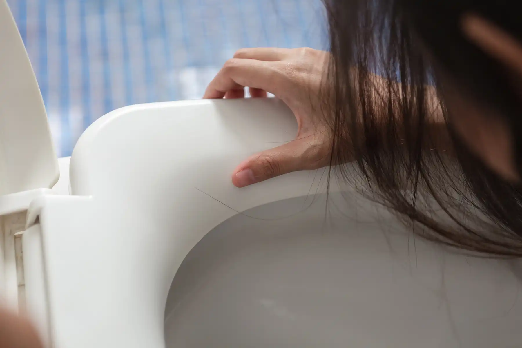 Girl leaning over a toilet.