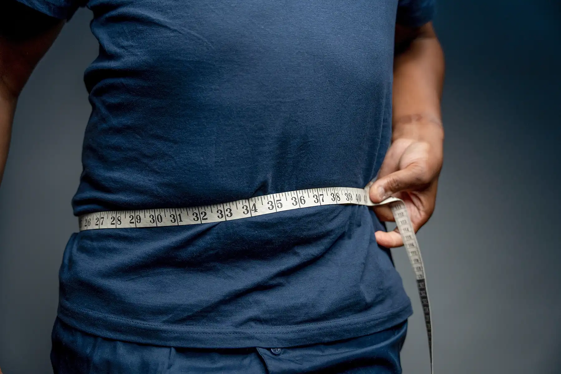 Man measuring his waist with a tape measure.