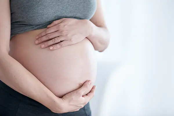 Pregnant woman holding her hands to her belly.